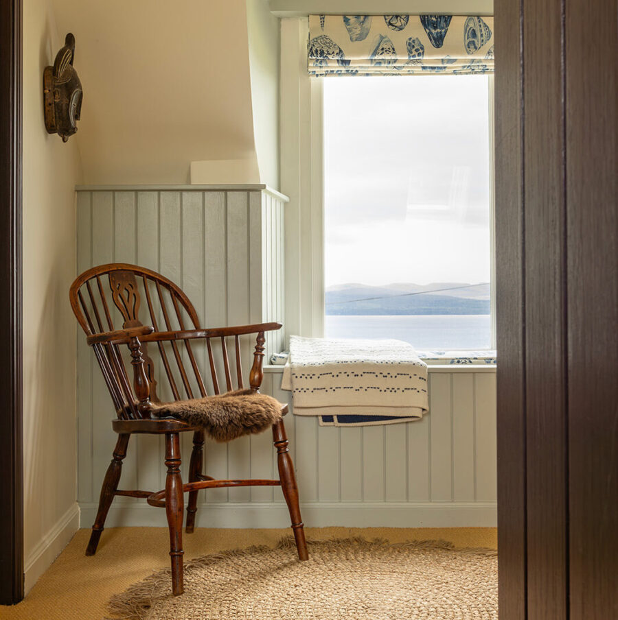 On the landing with dormer window at the Croft House cottage at Geary, Skye, Scotland. A view to the sea, a stick back windsor chair.